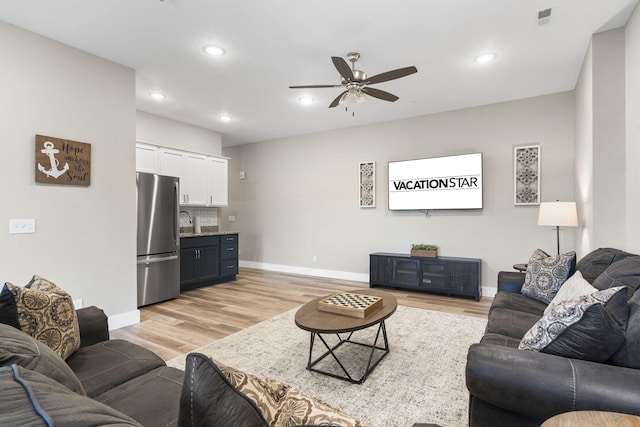 living room featuring sink, light hardwood / wood-style flooring, and ceiling fan