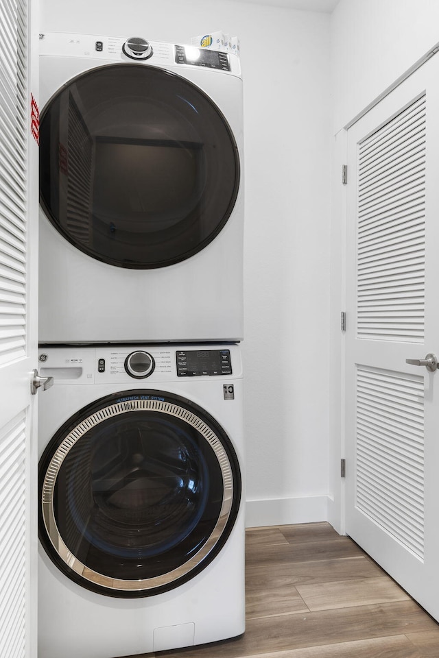 laundry area featuring light hardwood / wood-style floors and stacked washer / drying machine