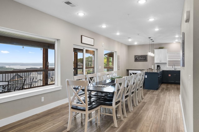 dining area with a water view, hardwood / wood-style floors, and sink