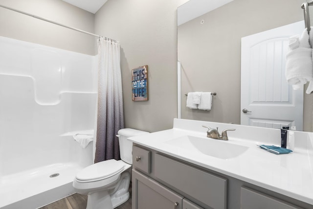 bathroom with hardwood / wood-style flooring, toilet, walk in shower, and vanity