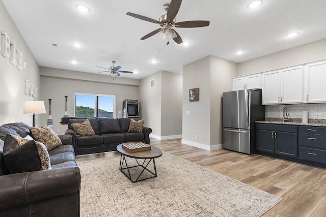 living room with sink, light wood-type flooring, and ceiling fan