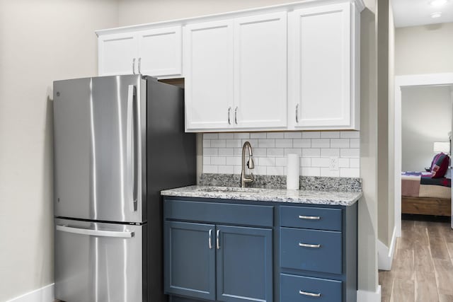 kitchen featuring stainless steel refrigerator and white cabinets