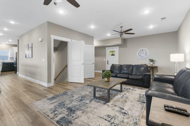 living room with light wood-type flooring and ceiling fan