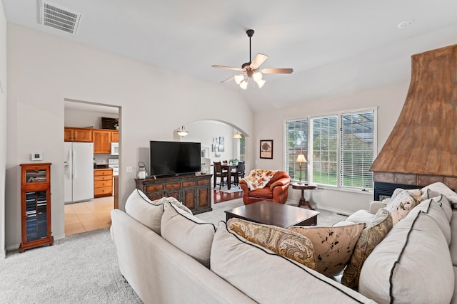 carpeted living room with a fireplace, ceiling fan, and vaulted ceiling