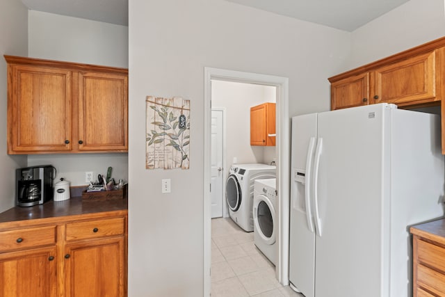 clothes washing area with cabinets, washing machine and dryer, and light tile patterned flooring