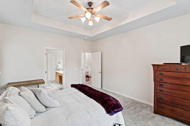 bedroom with ensuite bathroom, ceiling fan, light carpet, and a raised ceiling