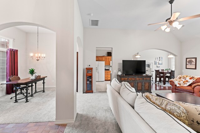 living room with ceiling fan with notable chandelier, high vaulted ceiling, and light colored carpet