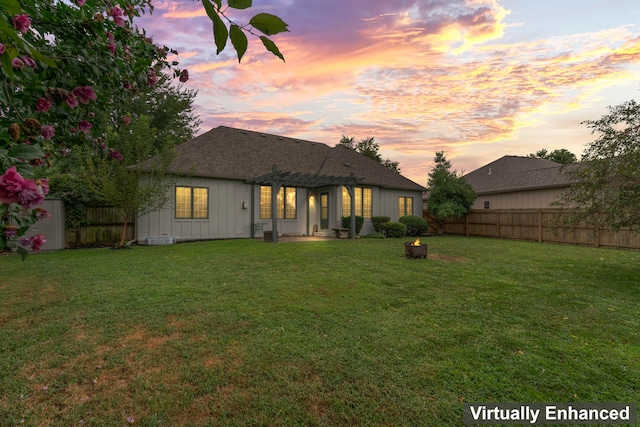 back house at dusk featuring a pergola and a lawn