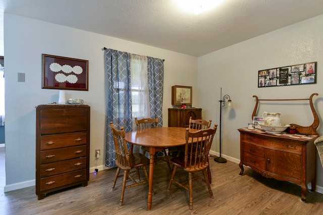 dining area featuring light hardwood / wood-style floors and a textured ceiling