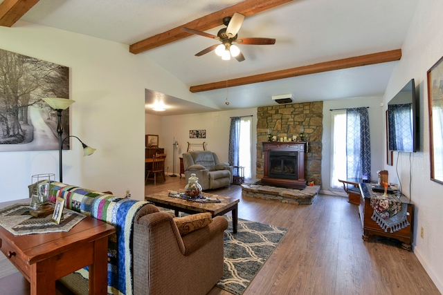 living room with lofted ceiling with beams, ceiling fan, a stone fireplace, and hardwood / wood-style floors