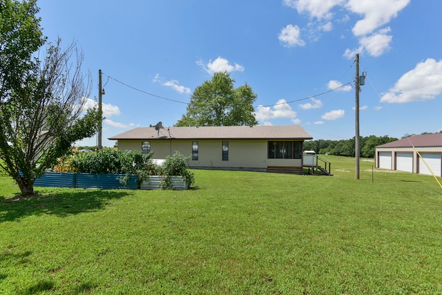 back of house featuring a garage, a sunroom, and a lawn