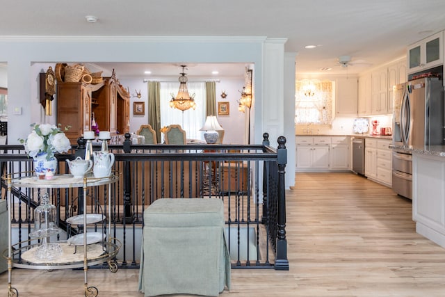 kitchen featuring white cabinets, ornamental molding, stainless steel appliances, and light hardwood / wood-style floors