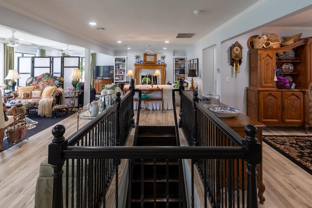 stairway with ornamental molding and hardwood / wood-style floors