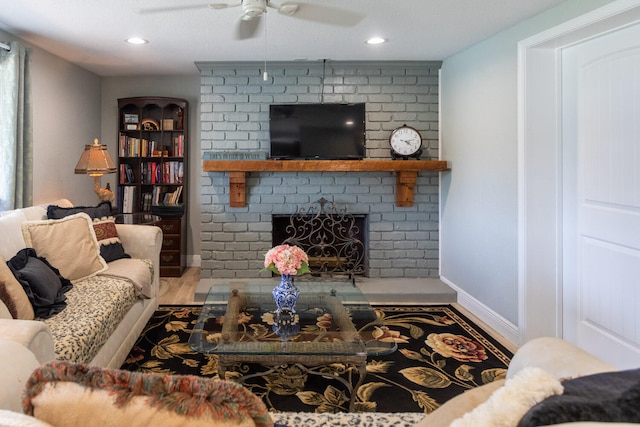 living room featuring a brick fireplace, hardwood / wood-style floors, and ceiling fan