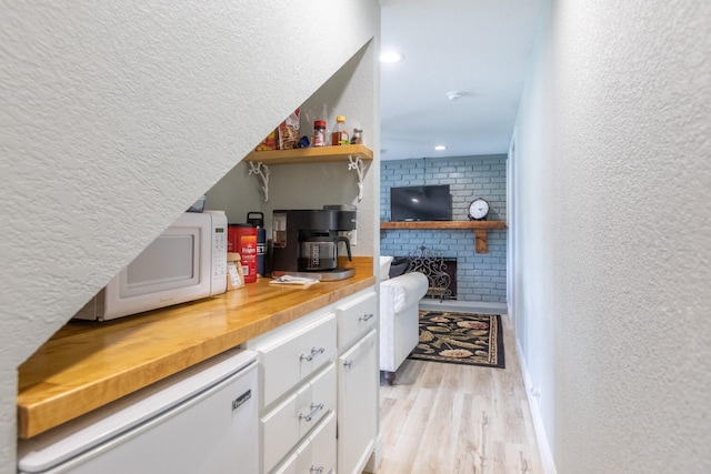 bar featuring a fireplace, light hardwood / wood-style floors, butcher block countertops, and white cabinetry