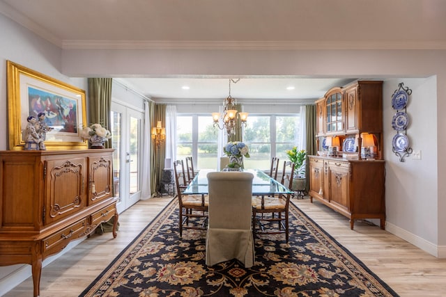 dining space featuring light hardwood / wood-style floors, crown molding, and a notable chandelier