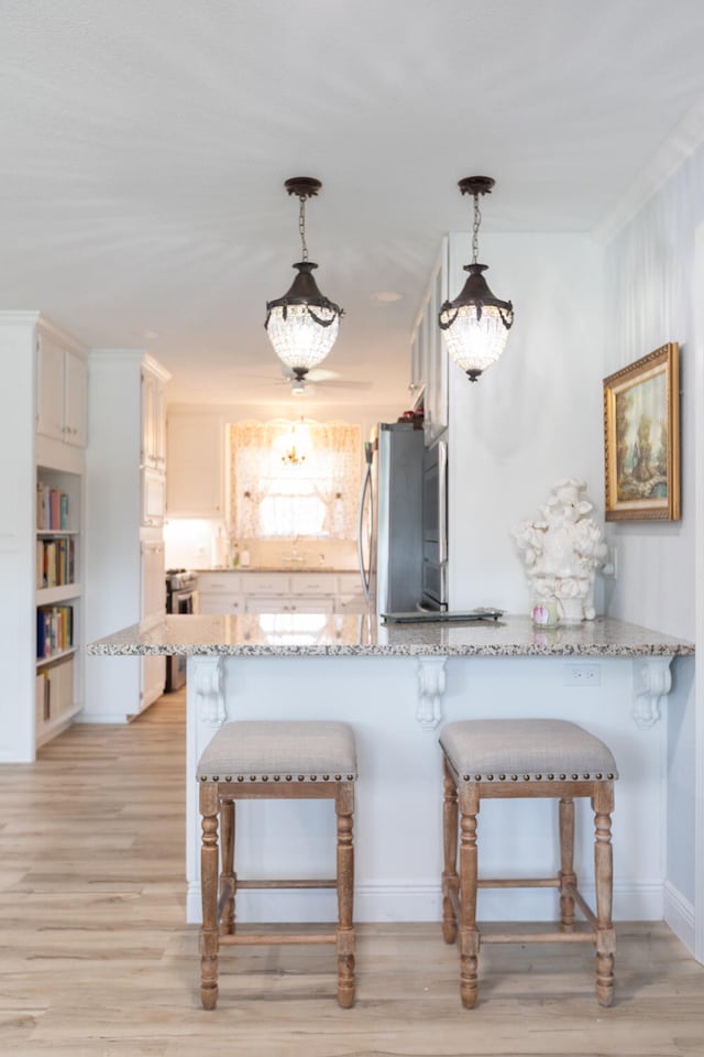 kitchen with white cabinets, stainless steel refrigerator, decorative light fixtures, and kitchen peninsula