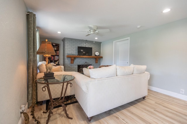 living room featuring a fireplace, light hardwood / wood-style flooring, and ceiling fan