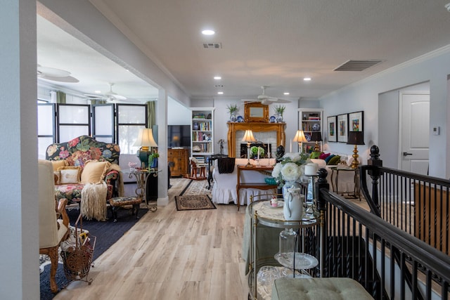 living room with ceiling fan, light wood-type flooring, and crown molding