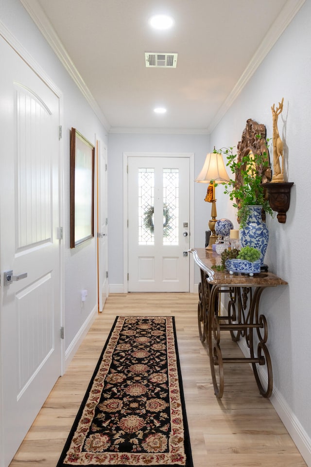 entryway with light hardwood / wood-style flooring and crown molding