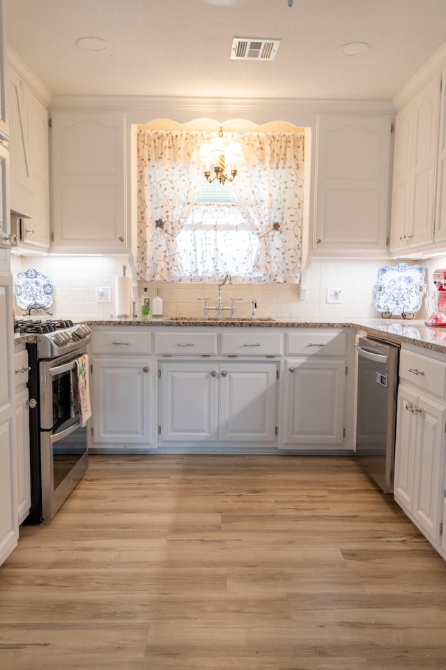 kitchen featuring light stone counters, sink, white cabinetry, appliances with stainless steel finishes, and light wood-type flooring