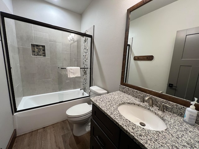 full bathroom featuring combined bath / shower with glass door, toilet, wood-type flooring, and vanity