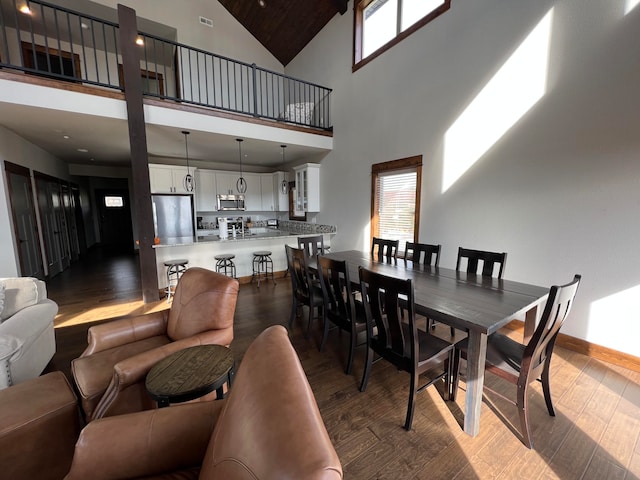 dining space featuring high vaulted ceiling, plenty of natural light, and dark hardwood / wood-style floors