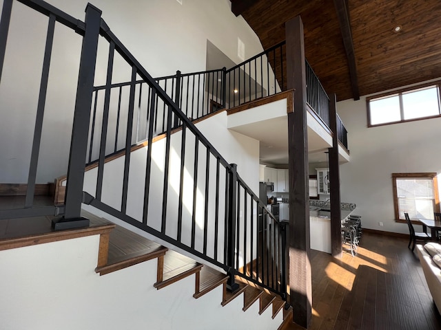 staircase with hardwood / wood-style flooring, wood ceiling, beam ceiling, and high vaulted ceiling