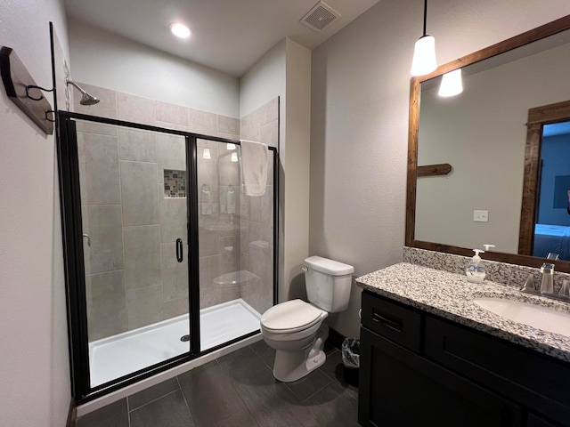 bathroom featuring a shower with shower door, vanity, and toilet