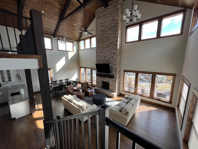 living room with a stone fireplace, wood ceiling, dark hardwood / wood-style flooring, and high vaulted ceiling