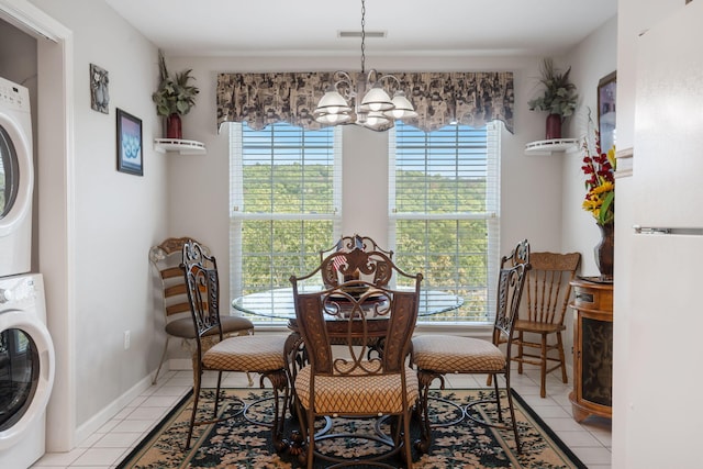 dining space featuring stacked washer and clothes dryer, an inviting chandelier, plenty of natural light, and light tile patterned floors