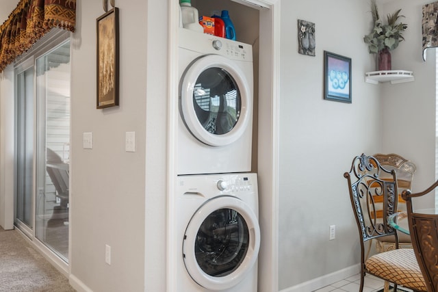 laundry area with stacked washer / drying machine and light tile patterned floors