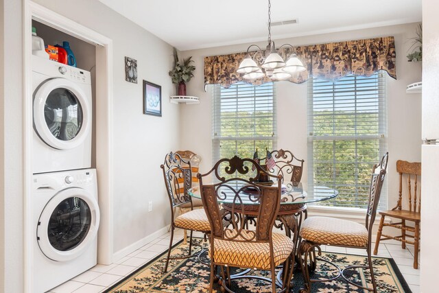 tiled dining room with stacked washer and clothes dryer, plenty of natural light, and a chandelier