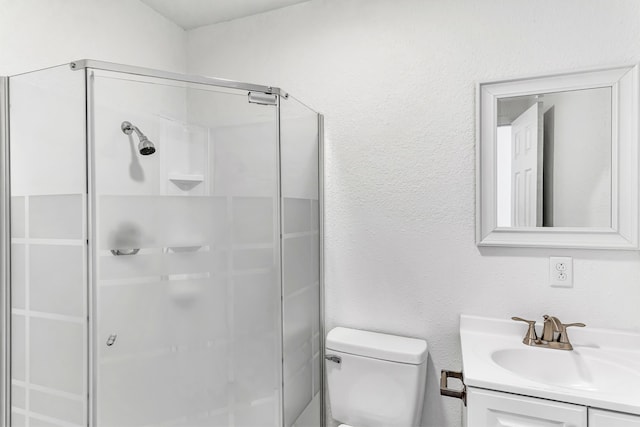 bathroom featuring toilet, vanity, and a shower with shower door