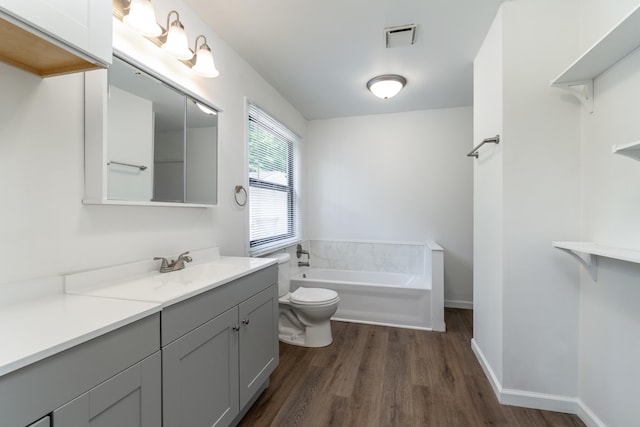 bathroom with wood-type flooring, vanity, toilet, and a washtub