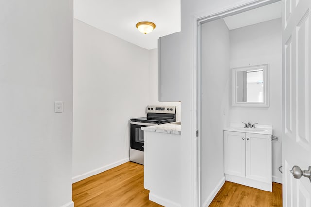 interior space with white cabinets, light hardwood / wood-style flooring, sink, and stainless steel electric range