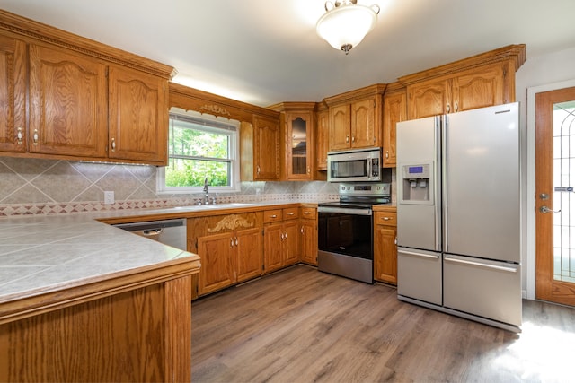 kitchen featuring sink, stainless steel appliances, backsplash, and light hardwood / wood-style floors