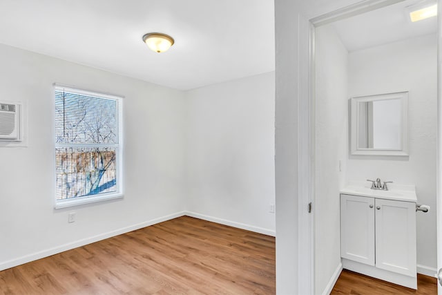empty room with an AC wall unit, sink, and light hardwood / wood-style flooring