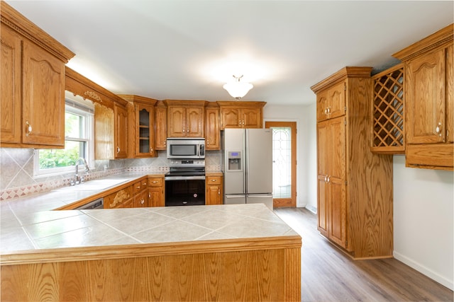 kitchen featuring light hardwood / wood-style flooring, stainless steel appliances, tile countertops, and decorative backsplash