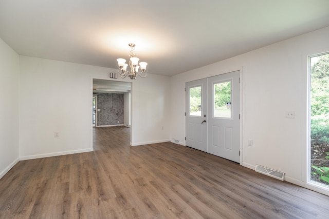 entryway with an inviting chandelier, plenty of natural light, and dark hardwood / wood-style flooring
