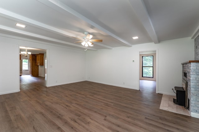 unfurnished living room with beamed ceiling, dark hardwood / wood-style floors, a wood stove, and a wealth of natural light