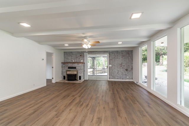 unfurnished living room with beam ceiling, dark hardwood / wood-style flooring, a wealth of natural light, and ceiling fan