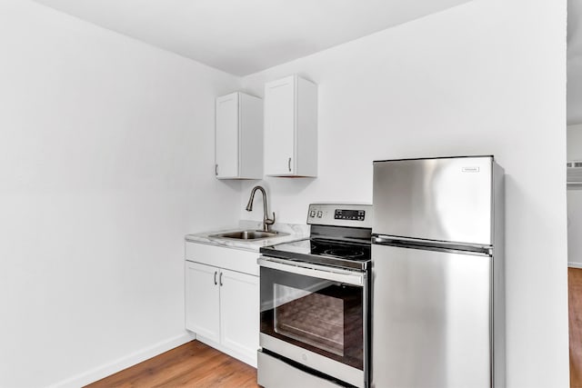 kitchen with white cabinets, stainless steel appliances, light wood-type flooring, and sink