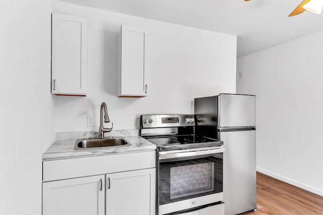 kitchen with light hardwood / wood-style flooring, appliances with stainless steel finishes, and white cabinetry