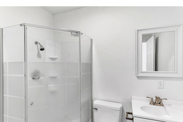 bathroom with a shower with door, vanity, and toilet