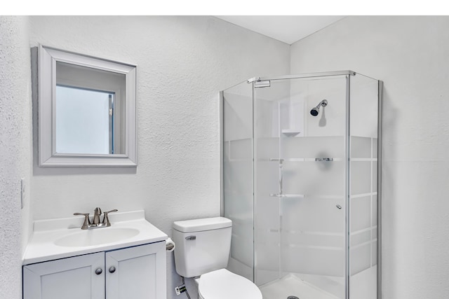 bathroom featuring vanity, a shower with door, and toilet