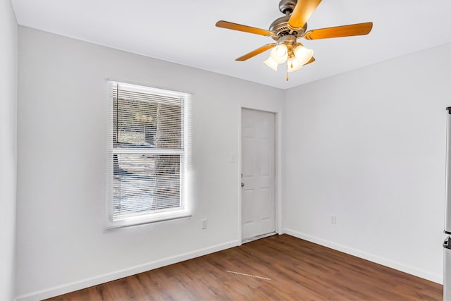 unfurnished room featuring ceiling fan, dark wood-type flooring, and a healthy amount of sunlight
