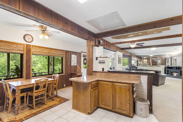 kitchen with light tile patterned flooring, kitchen peninsula, beam ceiling, and a textured ceiling