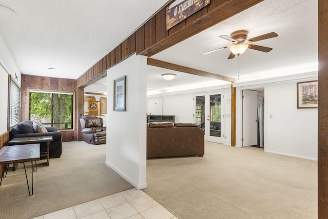 living room featuring a textured ceiling, wooden walls, ceiling fan, and light colored carpet