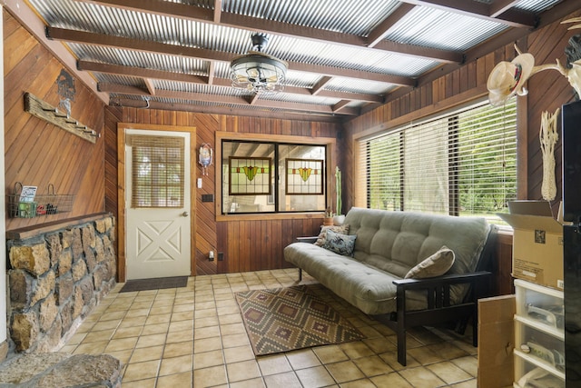 living room with wood walls, light tile patterned flooring, and beam ceiling